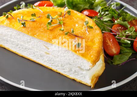 Uova francesi strapazzate omelette di Poulard con montatura bianca primo piano sul piatto su sfondo scuro. Orizzontale Foto Stock