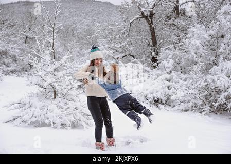 Mamma e figlio camminano nella neve nella foresta invernale. Foto Stock