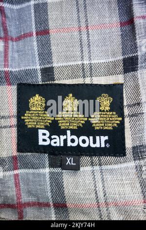 Primo piano di Barbour Dress Tartan fodera e su appuntamento a sua Maestà la cresta della Regina reale cucita all'interno di una giacca Barbour cerata Foto Stock