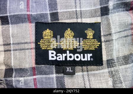 Primo piano di Barbour Dress Tartan fodera e su appuntamento a sua Maestà la cresta della Regina reale cucita all'interno di una giacca Barbour cerata Foto Stock