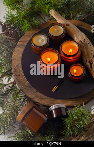 Le candele di soia bruciano in vasi di vetro. Comfort a casa. Candela in un vaso marrone. Profumo e luce. Candela profumata fatta a mano. Aromaterapia. Albero di Natale e umore invernale. Arredamento accogliente. Decorazione festiva Foto Stock