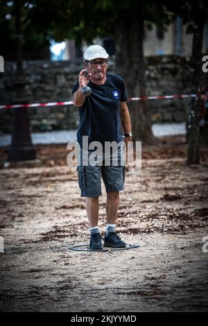 Un giocatore lancia una palla, boule durante un tradizionale gioco francese di pétanque nella piazza del paese Foto Stock