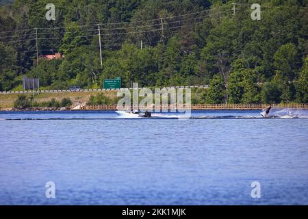 Uno sciatore d'acqua visto sul lago di Hunters Bay mentre il traffico verso nord passa a Hunstville, Ontario Foto Stock