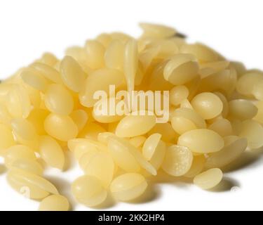 Una pila di perle di cera d'api gialle naturali isolate su uno sfondo bianco Foto Stock