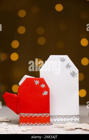 Origami di Natale - carta mitens, fallo voi stessi, sullo sfondo di bokeh ghirlande, un posto per il testo Foto Stock