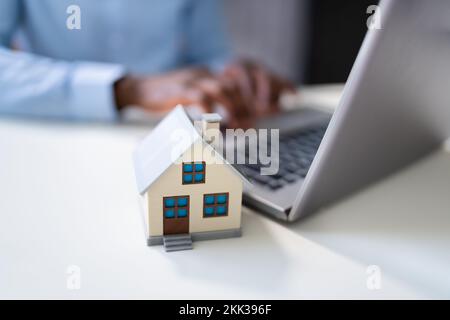 Modello Real Estate House vicino al computer portatile alla scrivania Foto Stock