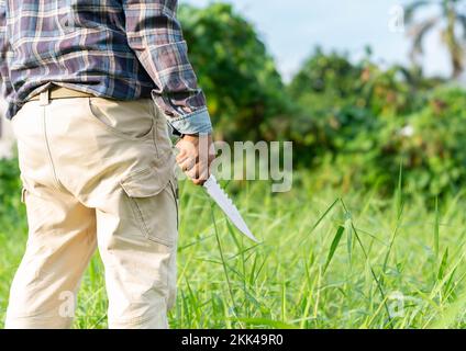 L'uomo tiene coltello da trekking in campo per il campeggio di viaggio. Foto Stock