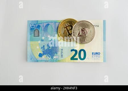 Bitcoin e Ethereum su una fattura di venti euro su sfondo bianco. Scambio di criptovaluta, concetto di investimento. Foto Stock