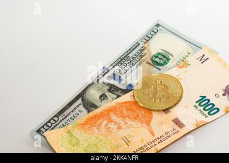 Bitcoin fisico oltre cento dollari e mille pesos argentini fattura. Cambio valuta, concetto di investimento internazionale. Foto Stock