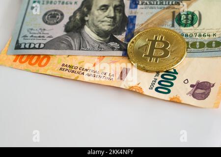 Bitcoin fisico oltre cento dollari e mille pesos argentini fattura. Cambio valuta, concetto di investimento internazionale. Foto Stock