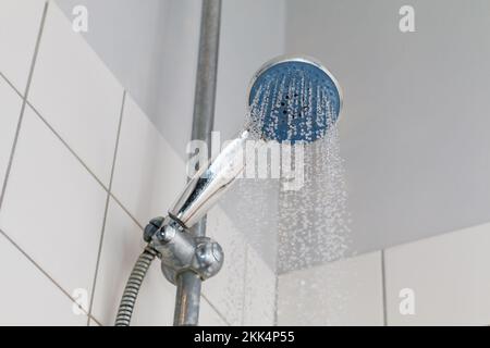 Acqua fredda corrente da un soffione doccia in un bagno. Foto Stock