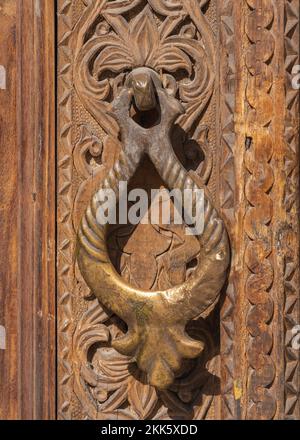 Vista in primo piano della tradizionale maniglia in ottone con design islamico sulla porta in legno intagliato di Kok Gumbaz madrasa, Istaravshan, regione di Sughd, Tagikistan Foto Stock