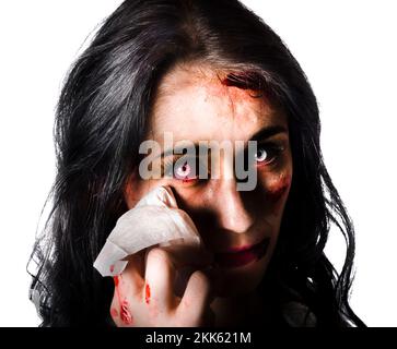 Lacrimoso donna con la macchia di sangue da lesioni facciali tergi il suo volto sul tessuto con sfondo bianco Foto Stock