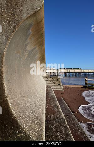 Il molo e parte del muro di mare a Teignmouth, mostrando i ritorni curvi che deviano le onde. Foto Stock