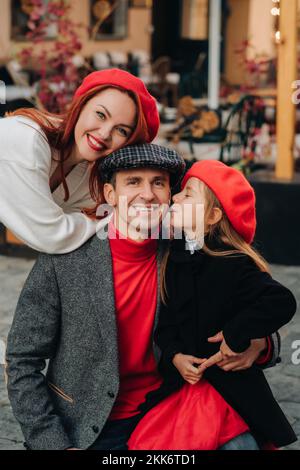 Una famiglia elegante di tre passeggiate attraverso la città autunnale in posa per un fotografo . Papà, mamma e figlia nella città d'autunno Foto Stock