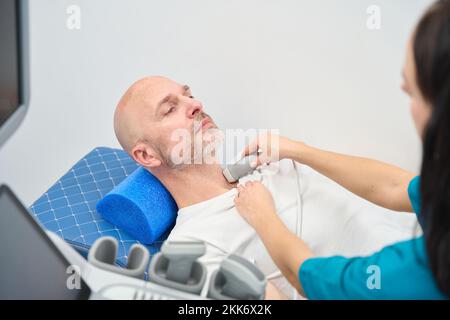 La donna esegue un esame ecografico del paziente nel collo Foto Stock