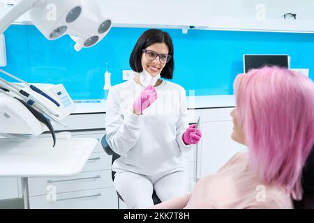 Il dentista sul posto di lavoro consulta una paziente di sesso femminile Foto Stock