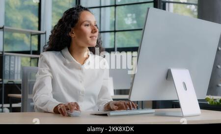 Giovane donna fidata professionista manager che lavora al computer digitando sulla tastiera positivo businesswoman si siede sul posto di lavoro nella ricerca di informazioni su Foto Stock