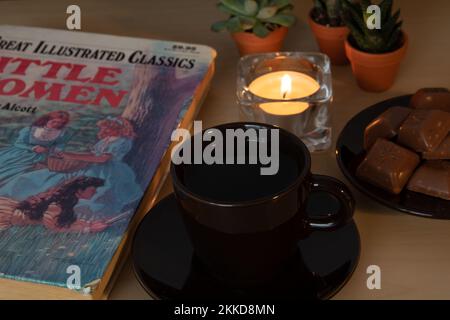 fototessera e libro con cioccolato su un piattino con candele Foto Stock