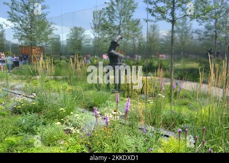 Vista panoramica sul giardino interno della mostra del padiglione polacco dell'Expo Milano 2015 con copia di una statua femminile, alberi e fiori. Foto Stock