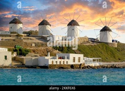 Mulini a vento di Mykonos di fronte ad uno spettacolare tramonto che illumina le nuvole con colori sullo sfondo. Foto Stock