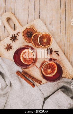 Due bicchieri con VIN brulé sul tagliere di legno con spezie e fette di arancia, vista dall'alto. Foto Stock