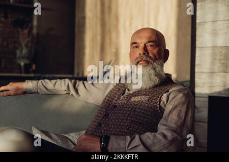 uomo bearded maturo seduto su una sedia. Foto Stock