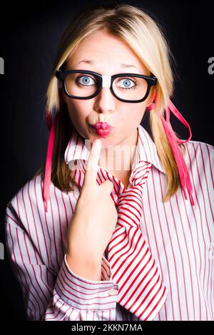 Giovane attraente ragazza bionda indossando occhiali dorky mette il dito indice per rugose labbra in un lavoro concetto segreti Foto Stock
