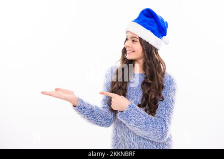 Inverno ragazza teen che punta sulla scpace della copia. Inverno bambino ritratto isolato. Ragazza adolescente in vacanza di Natale. Buon natale e Felice Anno Nuovo. Banner di Foto Stock