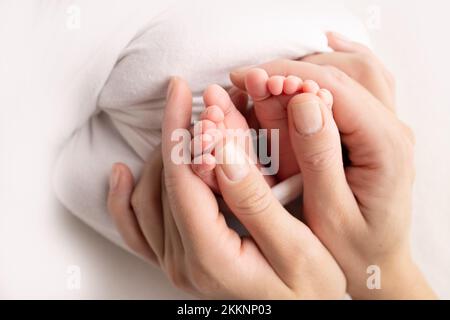 La madre sta facendo il massaggio sul suo piede del bambino. I piedi del bambino nelle mani della madre su un bianco. Foto Stock