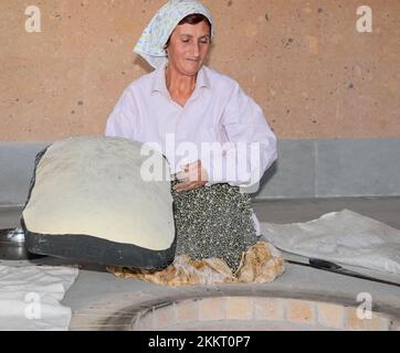 Le donne che cuocono il tipico pane armeno di lavash nel forno di terra 'tonir', Abovyan, Armenia Foto Stock