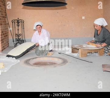 Le donne che cuocono il tipico pane armeno di lavash nel forno di terra 'tonir', Abovyan, Armenia Foto Stock