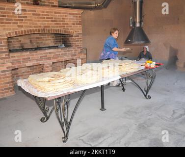 Le donne che cuocono il tipico pane armeno di lavash nel forno di terra 'tonir', Abovyan, Armenia Foto Stock