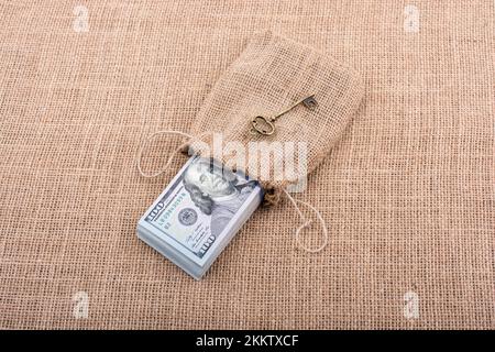 Chiave retrò e il pacchetto del dollaro USA in un sacco su una tela di canapa Foto Stock