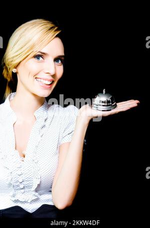 Bella donna bionda con un sorriso delizioso e un'espressione attenta tenendo una campana di servizio d'argento nella sua mano epitomizing il Vecchio Adagio del Servizio con Foto Stock