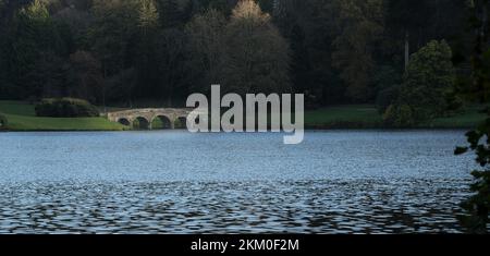 I cinque archi di grado i elencati palladiano ponte di pietra visto attraverso il lago a Stourhead, Wilts UK Foto Stock