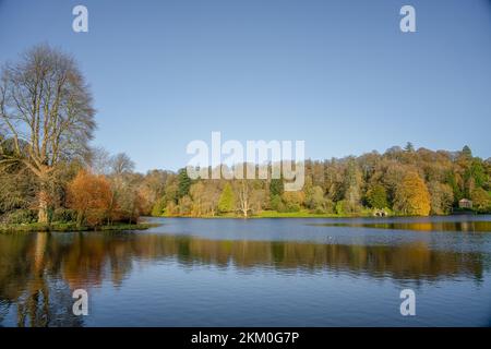 Autunno pomeriggio sole illumina il bosco e l'isola nel lago, Stourhead estate Wiltshire Regno Unito Foto Stock