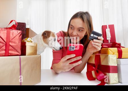Donna con i cani che acquistano regali online a casa Foto Stock