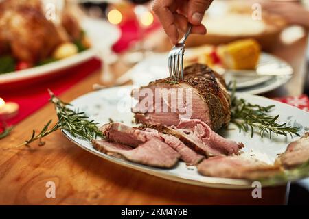 Mano, forchetta e manzo su una tavola di ringraziamento per la tradizione o la celebrazione nel primo piano di festa dall'alto. Cibo, carne e Natale con un posto Foto Stock