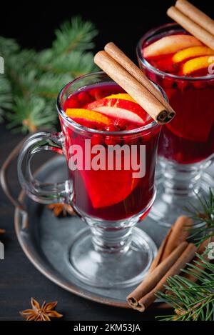 Due bicchieri con VIN brulé caldo con arancia e spezie su fondo ligneo. Foto Stock