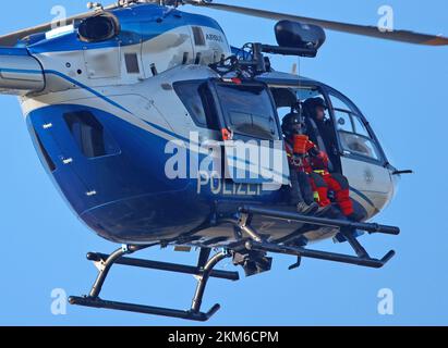 Ballenstedt, Germania. 26th Nov 2022. Un elicottero di polizia porta un membro della squadra di salvataggio di montagna Harz con un verricello sopra il massiccio di montagna sul Gegensteinen. I 20 membri di Bergwacht, addestrati al salvataggio aereo, devono mettere regolarmente in pratica le loro conoscenze teoriche. In totale, questo è il quarto giorno di esercizio con la polizia. Credit: Matthias Bein/dpa/Alamy Live News Foto Stock