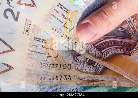 Diverse note di duecento zloty polacchi vengono trasferite e tenute in mano Foto Stock