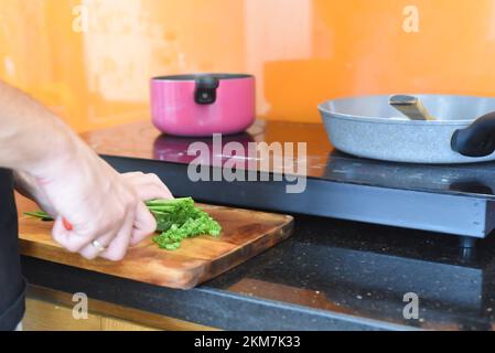 i maschi tagliano la cipolla verde su un asse di legno per cucinare ramen giapponesi Foto Stock