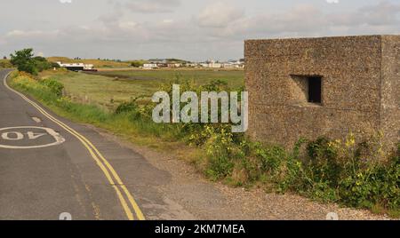 Un vecchio pillbox in tempo di guerra al Kench sull'Isola di Hayling, con case galleggianti sullo sfondo. Foto Stock
