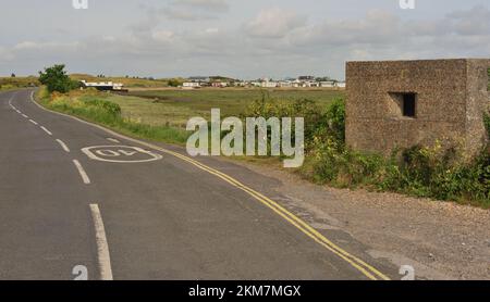 Un vecchio pillbox in tempo di guerra al Kench sull'Isola di Hayling, con case galleggianti sullo sfondo. Foto Stock