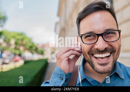 Giovane uomo adulto energico, che si prepara ad ascoltare musica mentre cammina fuori. Foto Stock