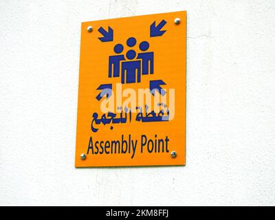 Assembly Point Sign in lingua araba e inglese che utilizza i messaggi di sicurezza per il protocollo di risposta alle emergenze, la conformità e uno strumento utile per aiutare le pubbliche relazioni Foto Stock