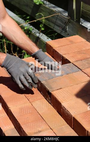 Mano dell'uomo che tiene il mattone rosso. Concetto di costruzione e costruzione. Ristrutturazione della casa in corso. Foto Stock