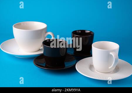 foto di due tazze e piattini marroni con due tazze bianche e piattini su sfondo blu Foto Stock