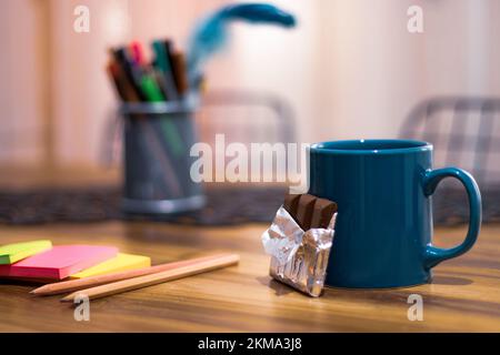 Tazza di caffè e cioccolato su tavolo di legno, carte da appunti colorate. Vista laterale, spazio di copia, primo piano. Cucina tavolo da pranzo, concetto di pausa Foto Stock